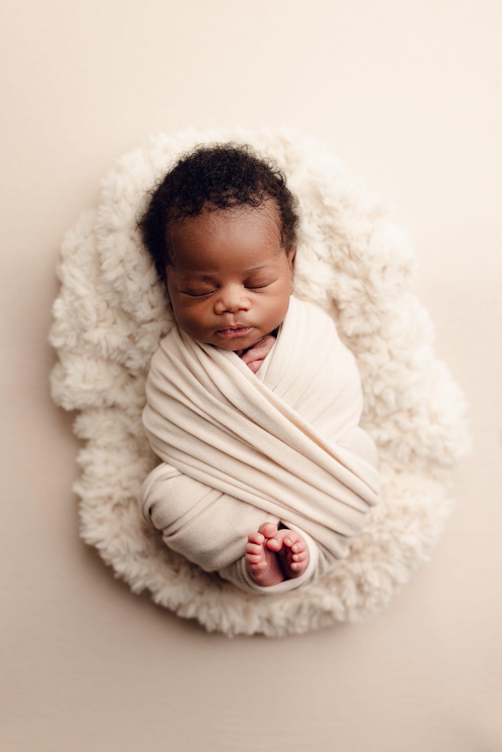 Sleeping newborn wrapped in a cream swaddle photographed by a Minnesota newborn photographer
