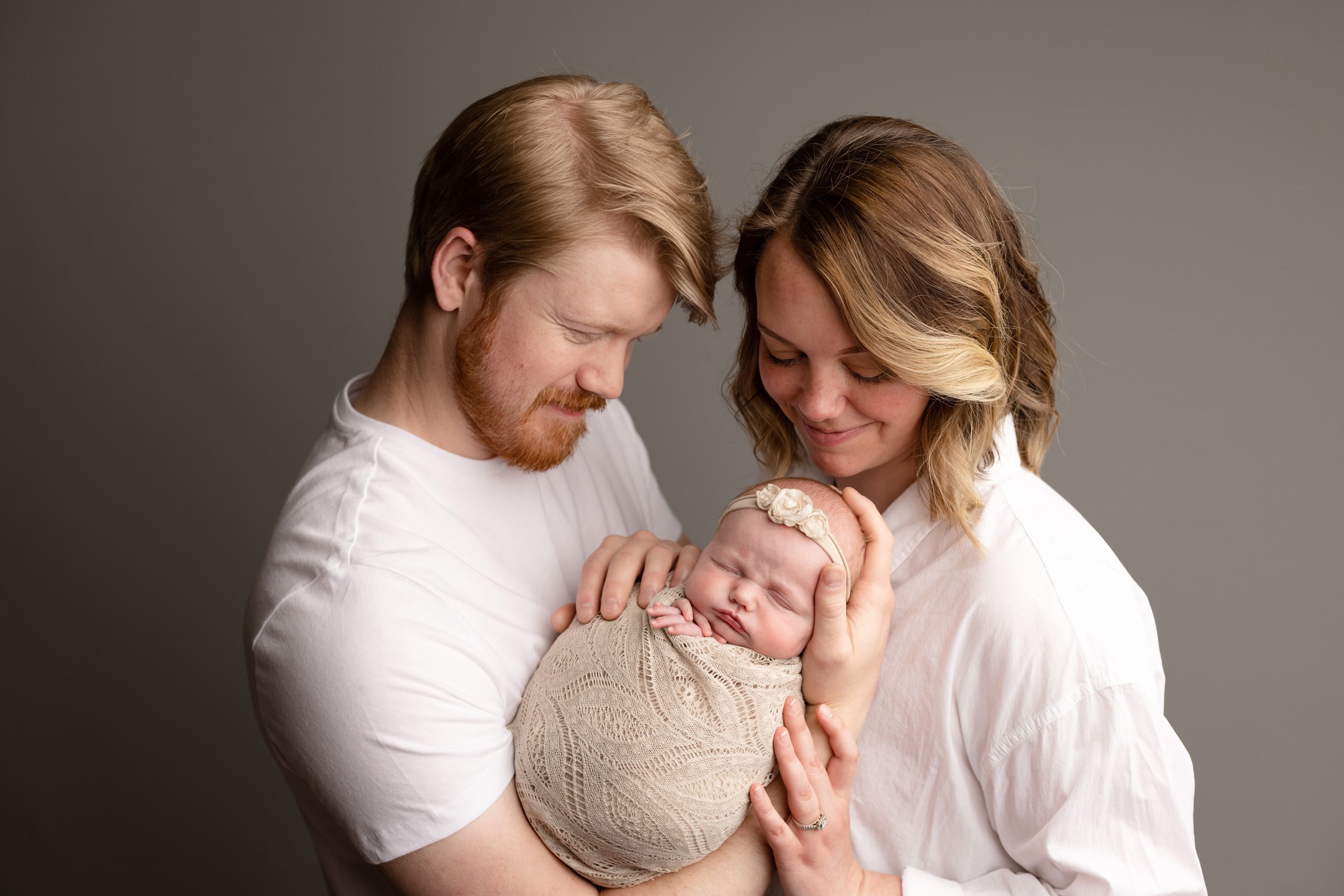 Mother and father holding their newborn baby during a professional newborn photography session in Blaine, MN.